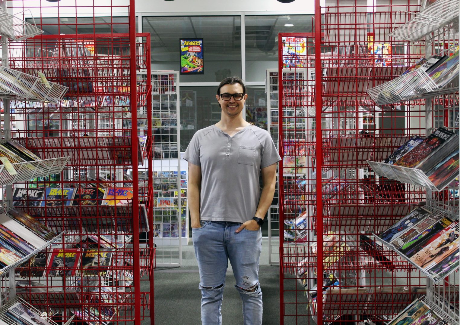 Director and Co-Owner of Mage's Comics, Eli Vida poses between shelves of comic books