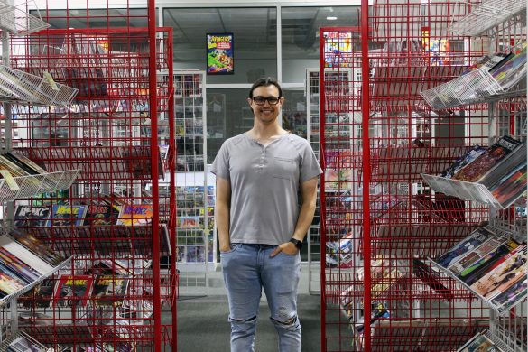 Director and Co-Owner of Mage's Comics, Eli Vida poses between shelves of comic books