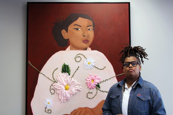 OIE Belonging Fellow & Art Curator Sy’mere Durrett stands next to mixed-media artist Jazlyn Gomez’s piece,“Y la Mia Tambien,” at the “Hasta Las Raíces: To the Roots, Embracing Heritage” gallery.