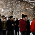 Group of students gathered outside in the snow to enjoy the holiday lighting