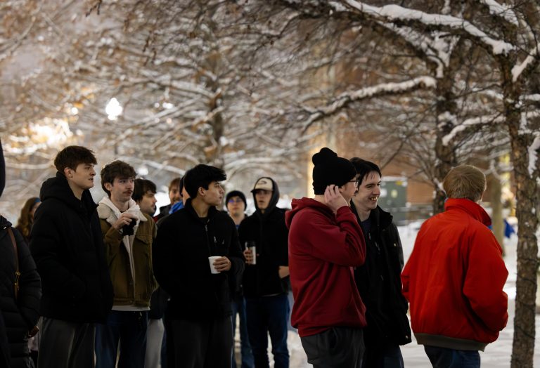 Group of students gathered outside in the snow to enjoy the holiday lighting