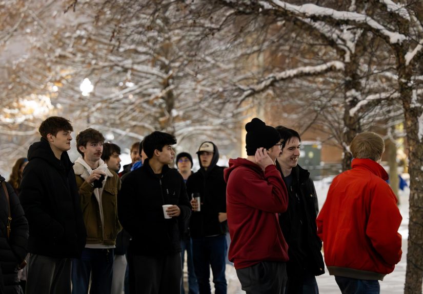 Group of students gathered outside in the snow to enjoy the holiday lighting