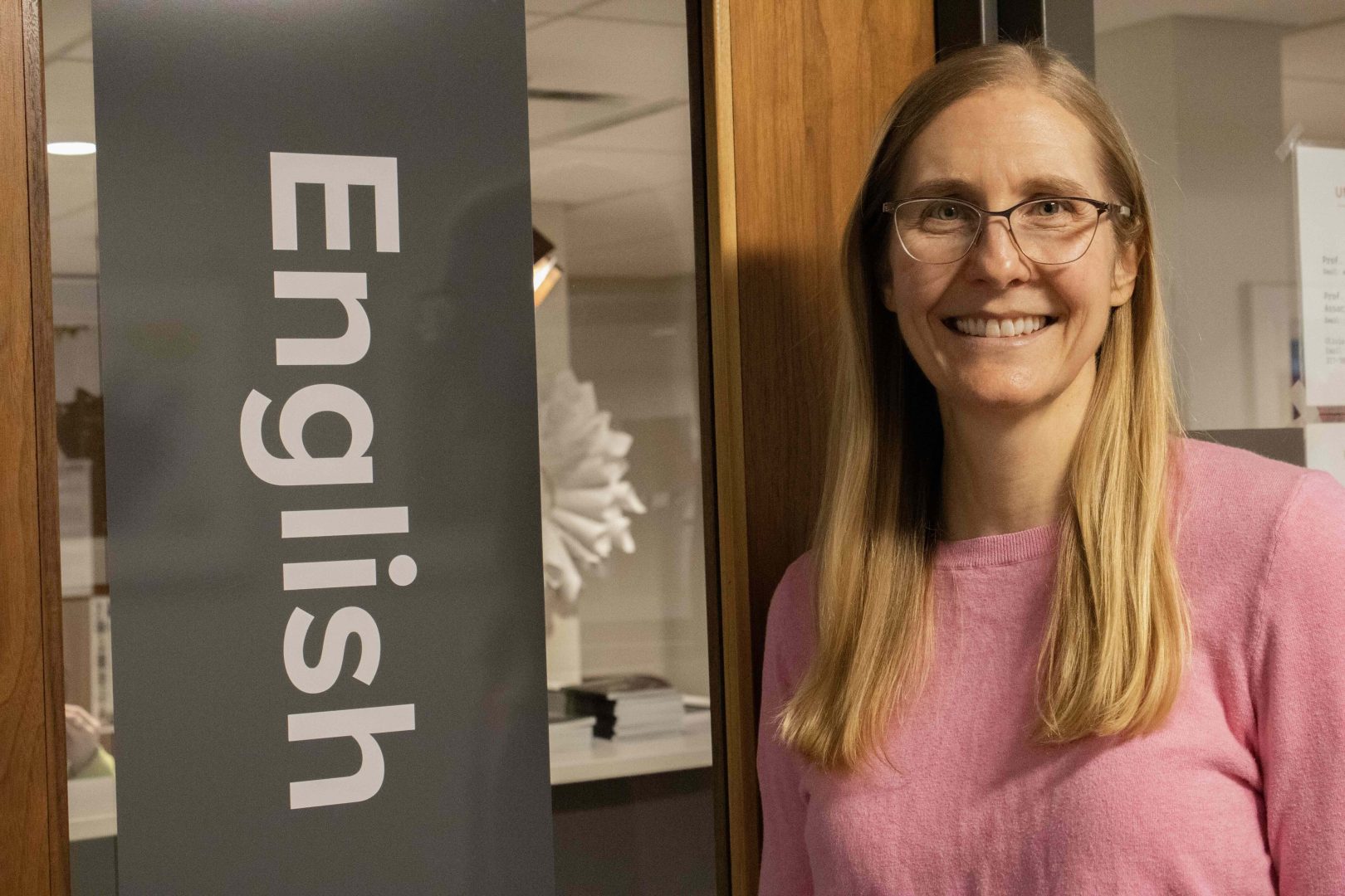 Professor Liz Whiteacre stands in front of English department doors.