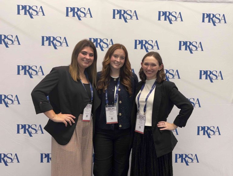Three girls stand together at the PRSA conference.