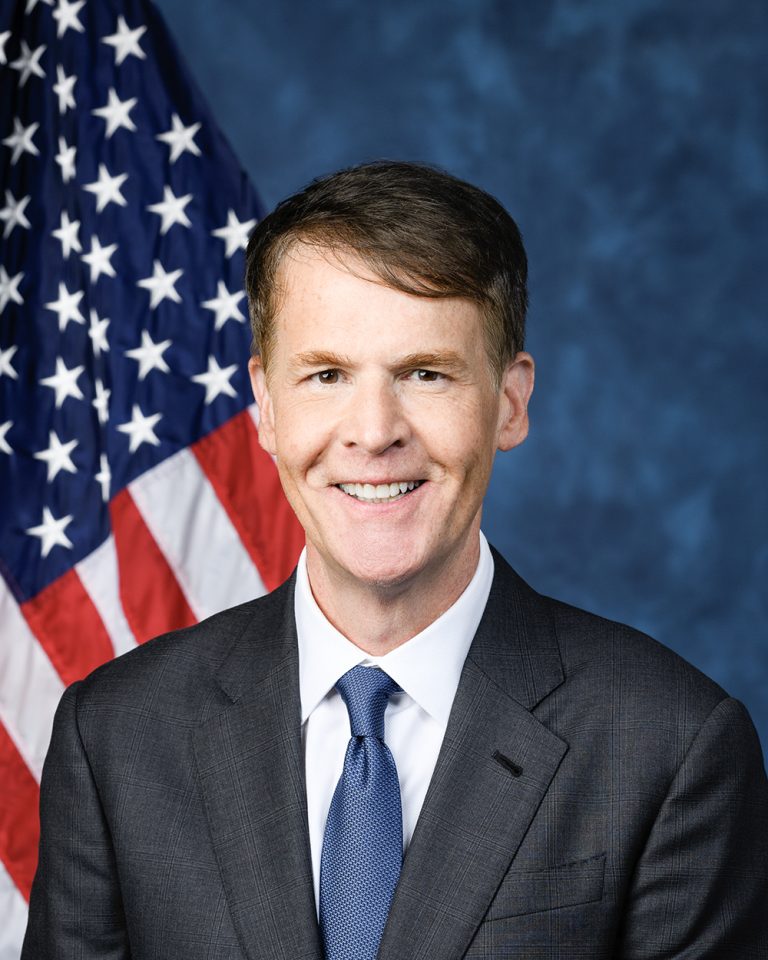 Jefferson Shreve smiling in front of an American flag